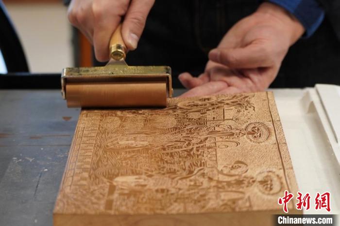 圖為徐晉林工作室工作人員正在給雕好壁畫的版面滾油墨。　九美旦增 　攝