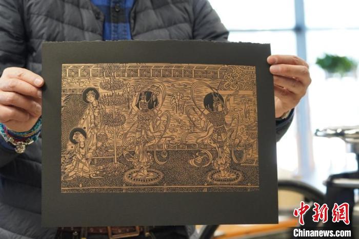 圖為手工書藝人展示敦煌雕版壁畫印刷品。　九美旦增 　攝