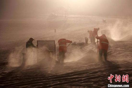 圖為敦煌市鳴沙山月牙泉景區(qū)“駱駝保姆”清理駱駝糞便?！垥粤?攝