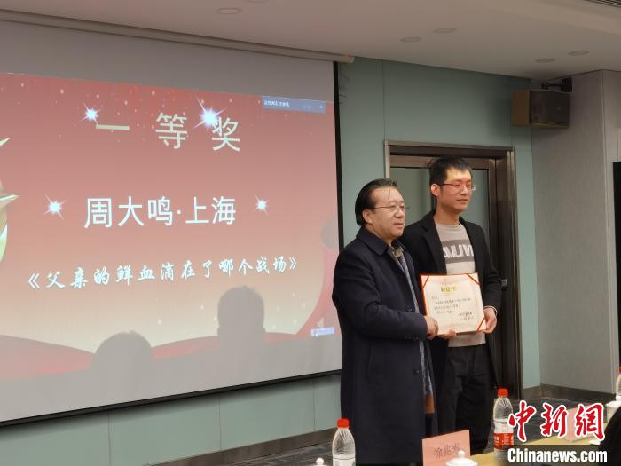 圖為作家、西北師范大學(xué)新聞與傳媒學(xué)院院長徐兆壽頒發(fā)一等獎證書，代領(lǐng)獎?wù)呱吓_領(lǐng)獎?！钅?攝