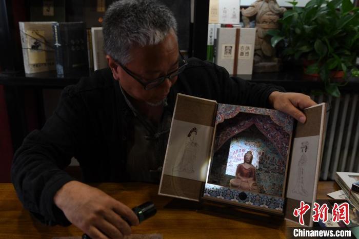 圖為讀者出版集團(tuán)讀者晉林工作室獨(dú)立出品人徐晉林，展示互動(dòng)性強(qiáng)的敦煌題材手工書。(資料圖) 楊艷敏 攝
