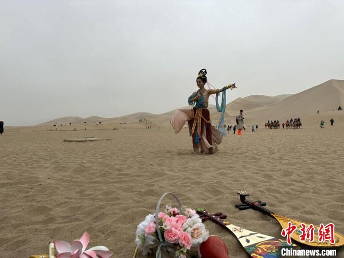 圖為2023年4月底，敦煌大漠“逐舞者”奧楠在鳴沙山月牙泉景區(qū)視頻直播敦煌舞。　馮志軍 攝