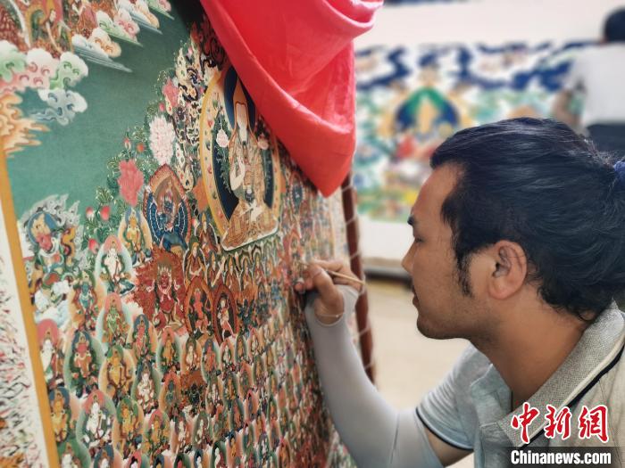 圖為更登才讓的徒弟繪畫唐卡?！?zhí)砀?攝
