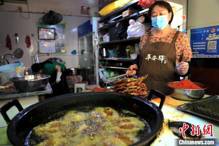圖為平安驛·河湟民俗文化體驗地內(nèi)的商戶炸干板魚?！⊙Φ?攝