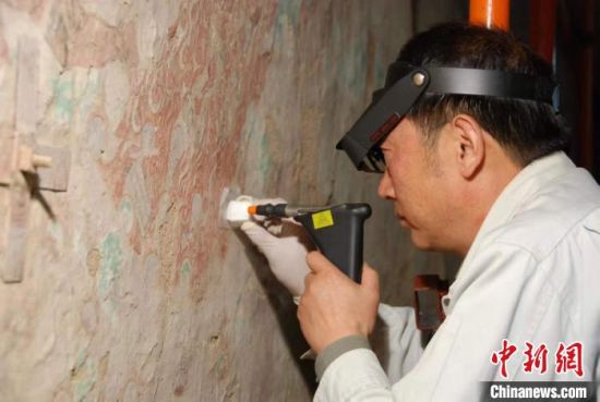敦煌研究院研究員樊再軒進行壁畫修復。(資料圖)張云文 攝